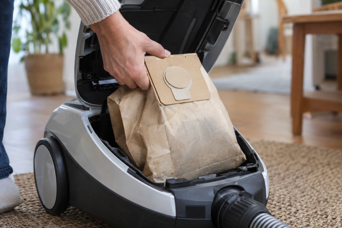 Sac d'aspirateur plein retiré de l'appareil et refermé avec sa languette